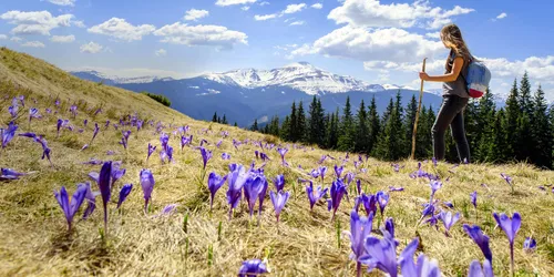 Eine Frau steigt auf einen Berg und blickt in die Ferne auf andere Berge