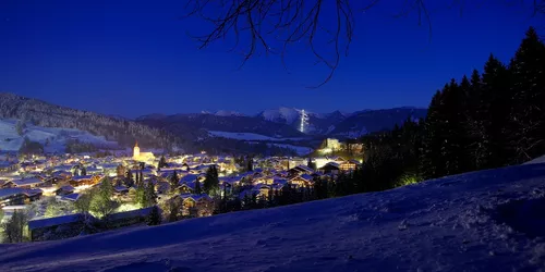 Verschneite Berglandschaft mit Blick auf beleuchteten Ort im Tal