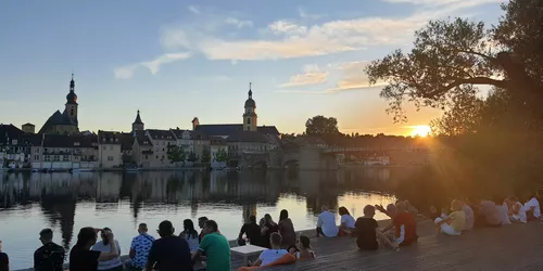 Menschen an Flussufer bei Dämmerung mit Blick auf Stadt