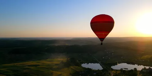 Roter Heißluftballon in der Luft bei Dämmerung