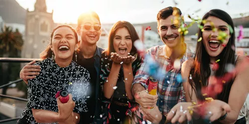 Gruppe von Freunden genießen Party und werfen Konfetti. Freunde, die sich auf der Dachterrasse amüsieren