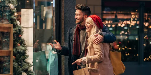 Junges Paar beim Weihnachtsshopping vor Schaufenster