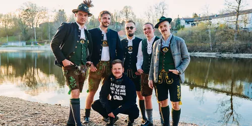 Männer mit bayerischer Tracht an einem Fluss