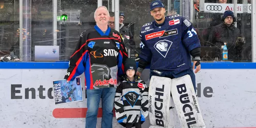 Man sieht einen Eishockeyspieler, der von zwei Fans des Vereins den Spieler des Monat Award bekommt.