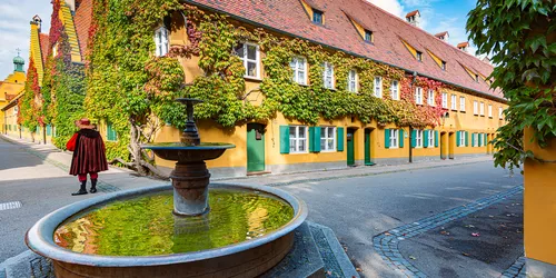 In den Gassen der alten Sozialviertel in Augsburg mit einem Brunnen im Zentrum einer Kreuzung