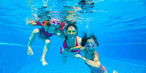 Eine Frau und zwei Mädchen beim Tauchen im Pool