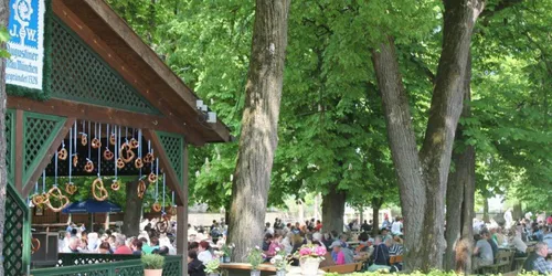 Blick auf Verkaufsstand, Menschen und Bäume im Augustiner Biergarten